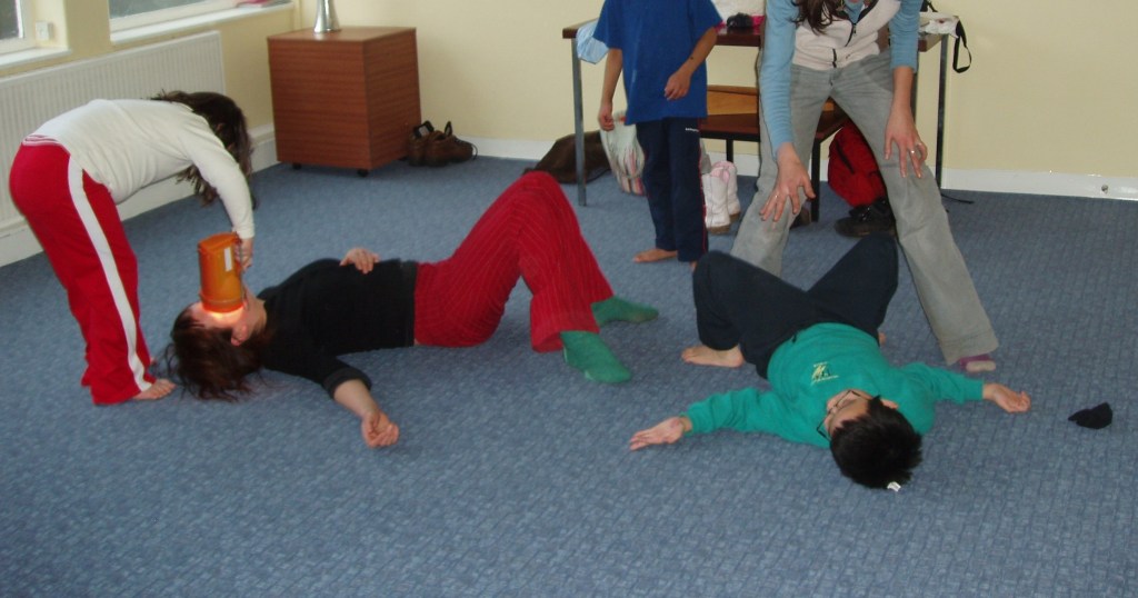 Children and adults participating in a dramatherapy session, acting and interacting in a creative space.