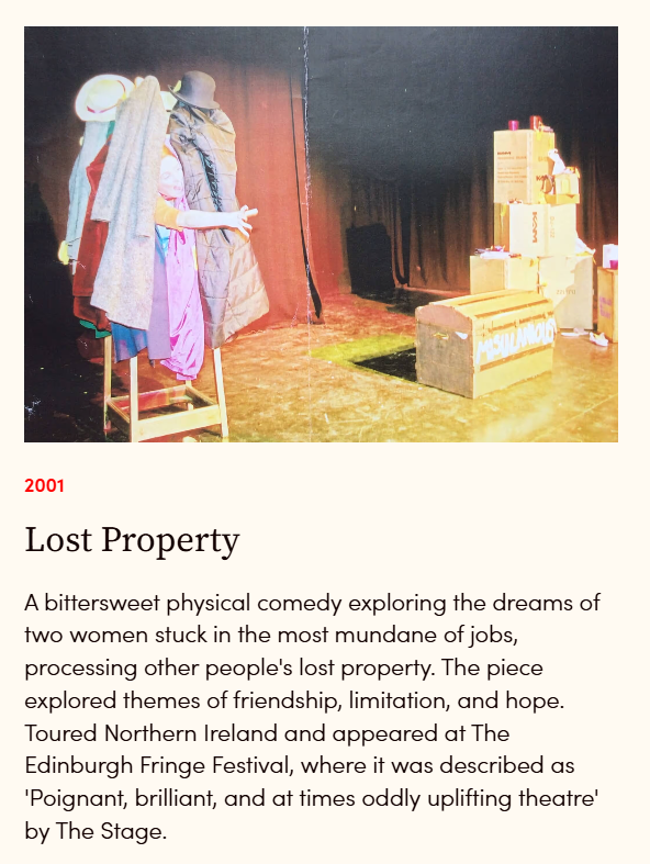 A stage set for a theatrical performance featuring two women in colorful costumes, surrounded by props including boxes and a ladder.